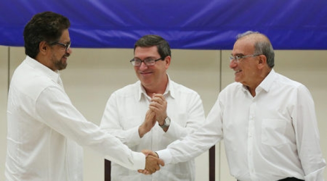  Иван Маркес от ФАРК (вляво) и преговарящият от страна на Богота Умберто де ла Кайе (вдясно) се ръкуват пред погледа на кубинския външен министър Бруно Родригес.