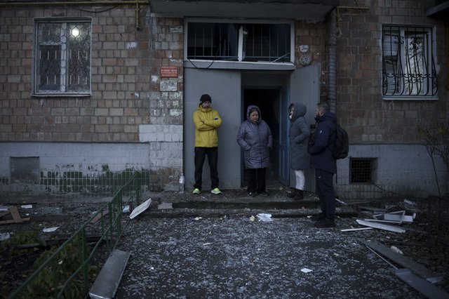 Хора стоят пред входа на жилищна сграда в Киев. Мястото е осеяно с отломки след руска атака с дронове срещу украинската столица, 25 ноември 2023 г. Снимка: АП/Felipe Dana