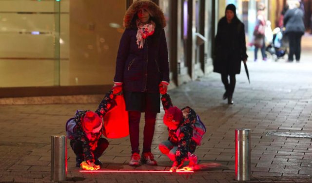 © ReutersЖена и двете й деца, които разглеждат новите осветителни ленти за пешеходци.