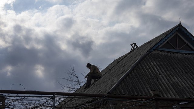 Мъж поправя постройка, която е повредена при руски обстрел, в град Константиновка, Донецка област. Снимка: АП