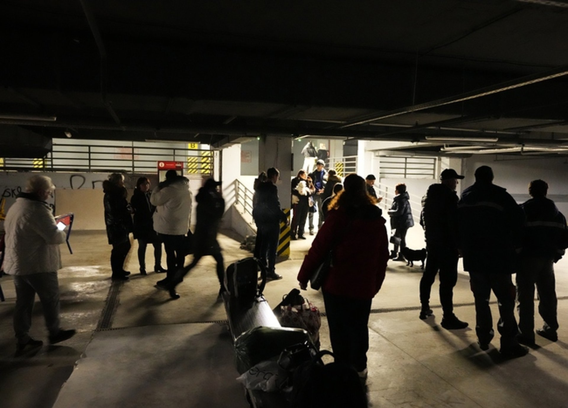 Хора стоят в подземен паркинг, използван като бомбоубежище, в търговски център в Одеса. Снимка: AP/Sergei Grits