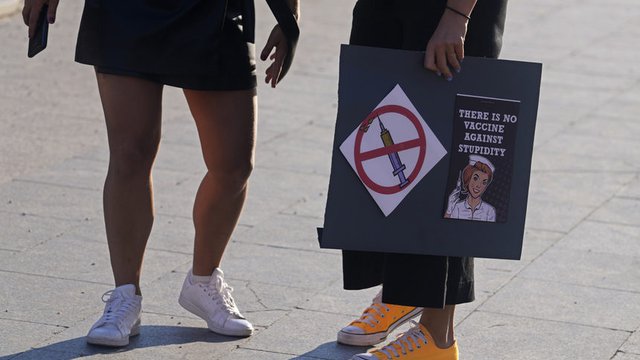 Жена носи банер "Няма ваксина срещу глупостта", част от правителствената кампания за насърчаване на ваксинацията, която позволи на Испания да се върне към най-ниските нива на разпространение на инфекцията.  © Associated Press