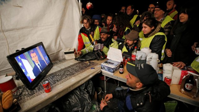 © ReutersПротестиращи с "жълти жилетки" гледат обръщението на президента Еманюел Макрон край Марсилия.
