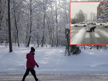 Мъж лази по заледена пешеходна пътека в Скопие, за да пресече
